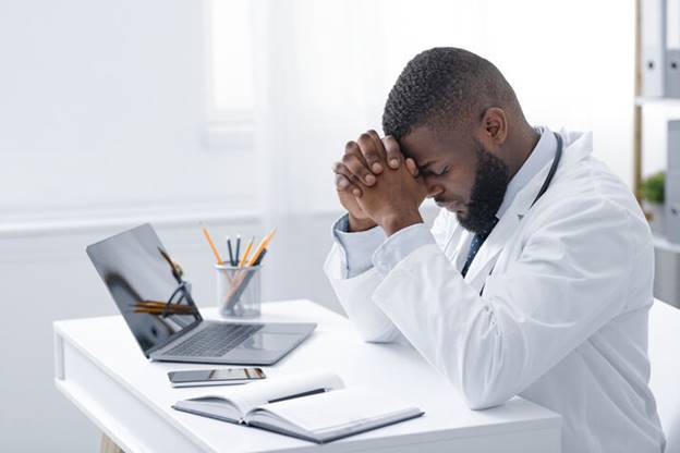 A doctor sitting at a desk with his hands together

AI-generated content may be incorrect.